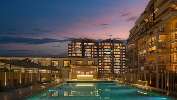 Ein Hotel mit Schwimmbad, mehreren Balkonen und einem gut beleuchteten Eingang.