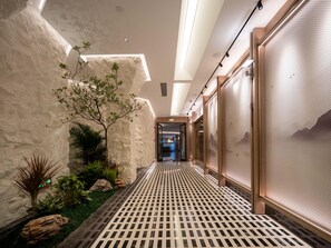 A hallway with a patterned floor, a plant, and a view into another room. - Holiday Inn Guilin Qixing by IHG (Guilin)