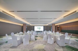A conference room with white chairs and tables, a projector screen, and a carpeted floor. - Holiday Inn Guilin Qixing by IHG (Guilin)