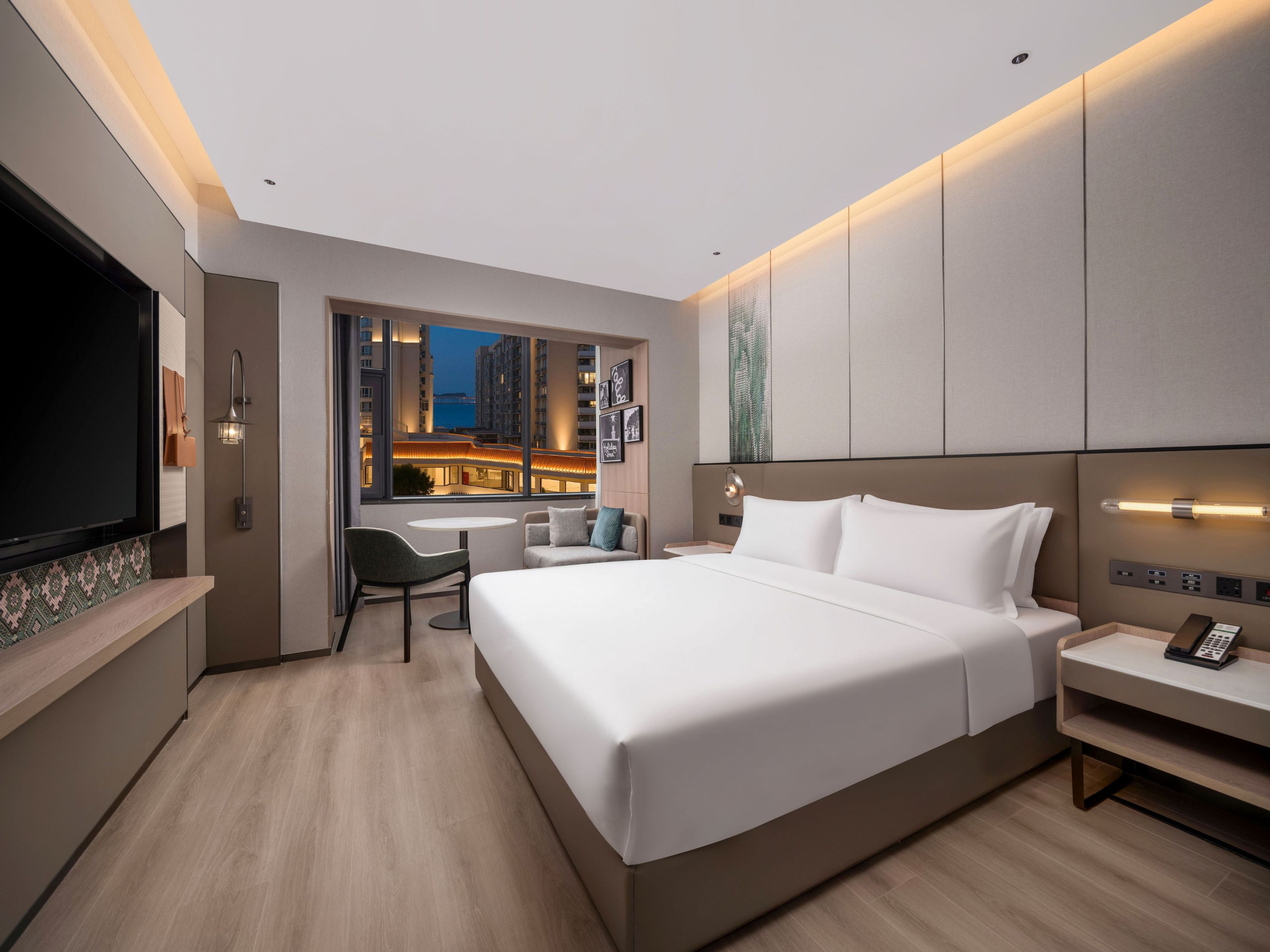 A modern hotel room with a large bed, a desk, and a TV.