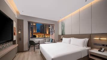 A modern hotel room with a large bed, a desk, and a TV.