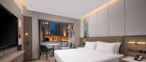 A modern hotel room with a large bed, a desk, and a TV.
