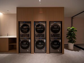 Fila de tres rentamàquines penjades a la paret, un rentapeus i una planta en test, tot en un interior modern.