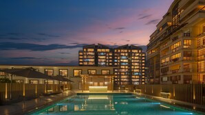 Un hotel con piscina, varios balcones y una entrada bien iluminada.