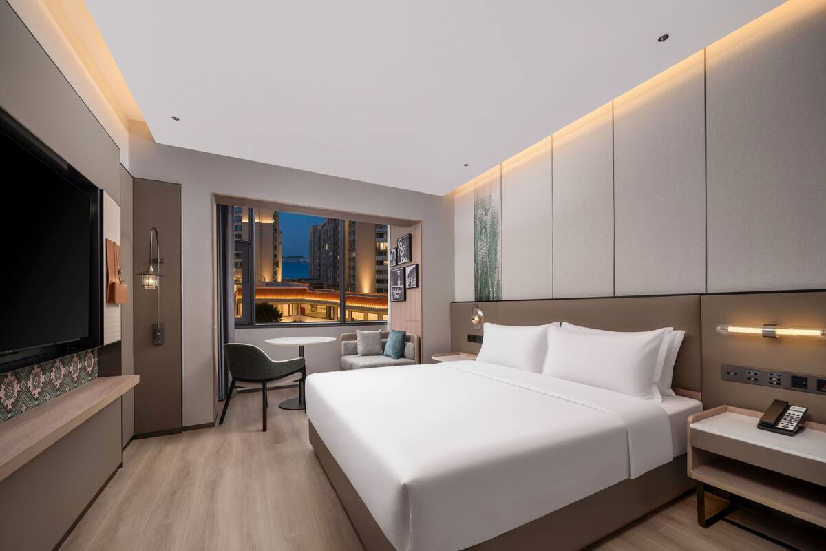 Una habitación de hotel moderna con una cama grande, un escritorio y un televisor.