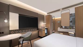 Quarto de hotel moderno com uma cama, uma mesa de trabalho, uma cadeira, toucador com espelho e área de chuveiro.