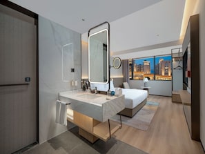 A modern hotel room with a large bed, a bathroom with a marble vanity, a large mirror, and a city view through the window. - Holiday Inn Guilin Qixing by IHG (Guilin)