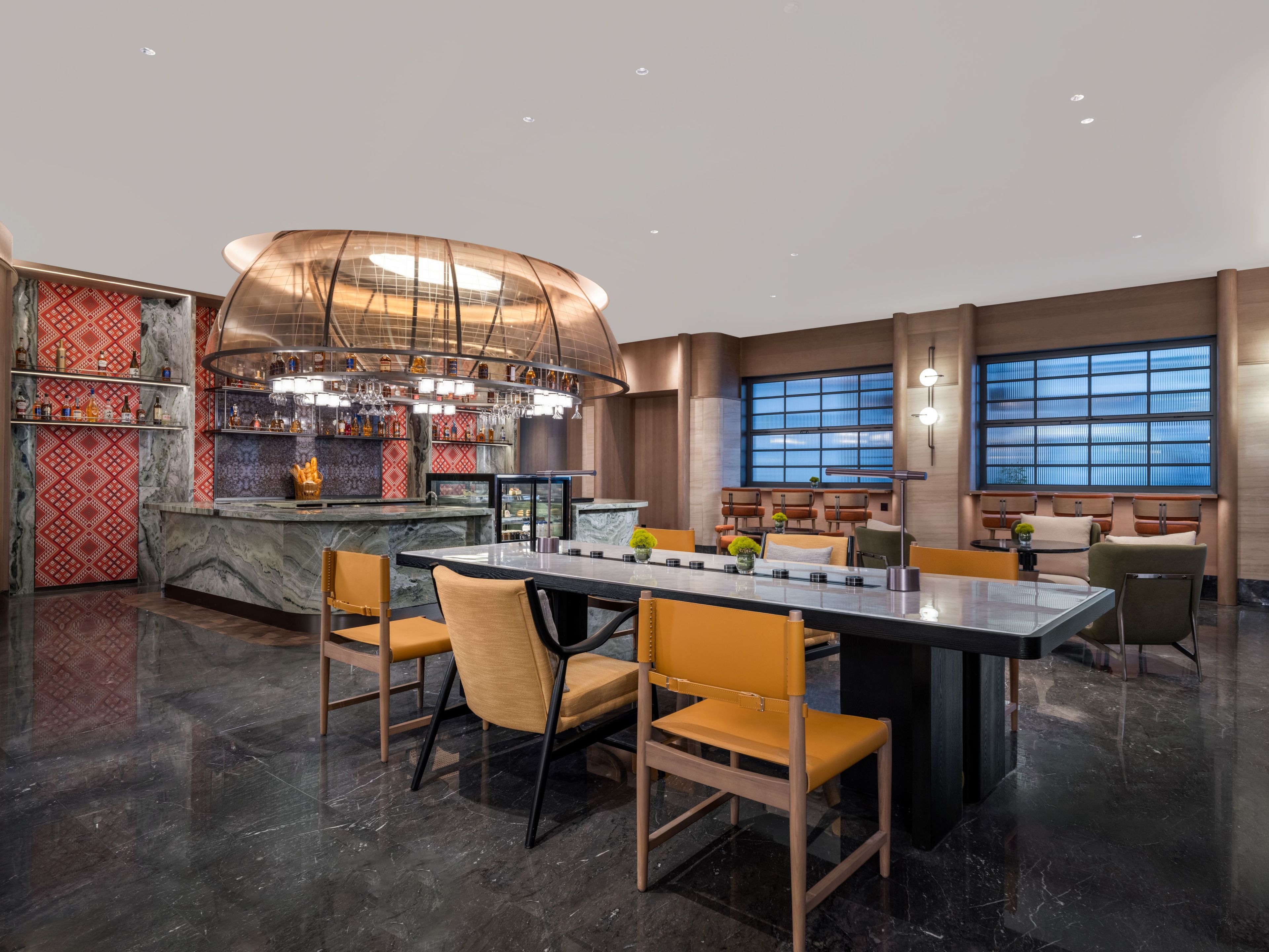 A modern bar area with a curved ceiling, marble countertops, and a variety of bottles and glasses.