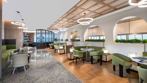 Eine moderne Hotelhalle mit verschiedenen Sitzbereichen, einer Bar und einer Rezeption.