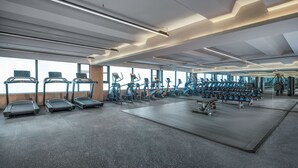 Ein modernes Fitnessstudio mit Laufbändern, Crosstrainern und Gewichtecken.