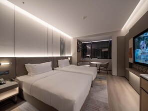 Una habitación de hotel con dos camas, televisión, escritorio y ventana.