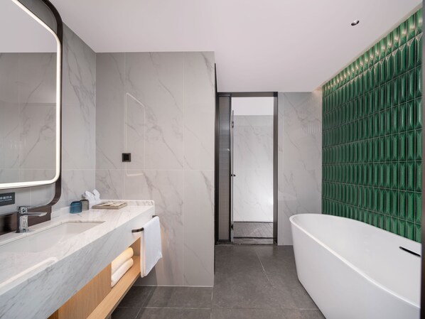 A modern bathroom with a marble vanity, a large mirror, a white bathtub, and green patterned tiles. - Holiday Inn Guilin Qixing by IHG (Guilin)