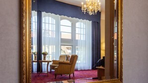 A room with a large mirror, a chandelier, and a view of the outside through large windows. - Hotel Erbprinzenpalais (Wernigerode)