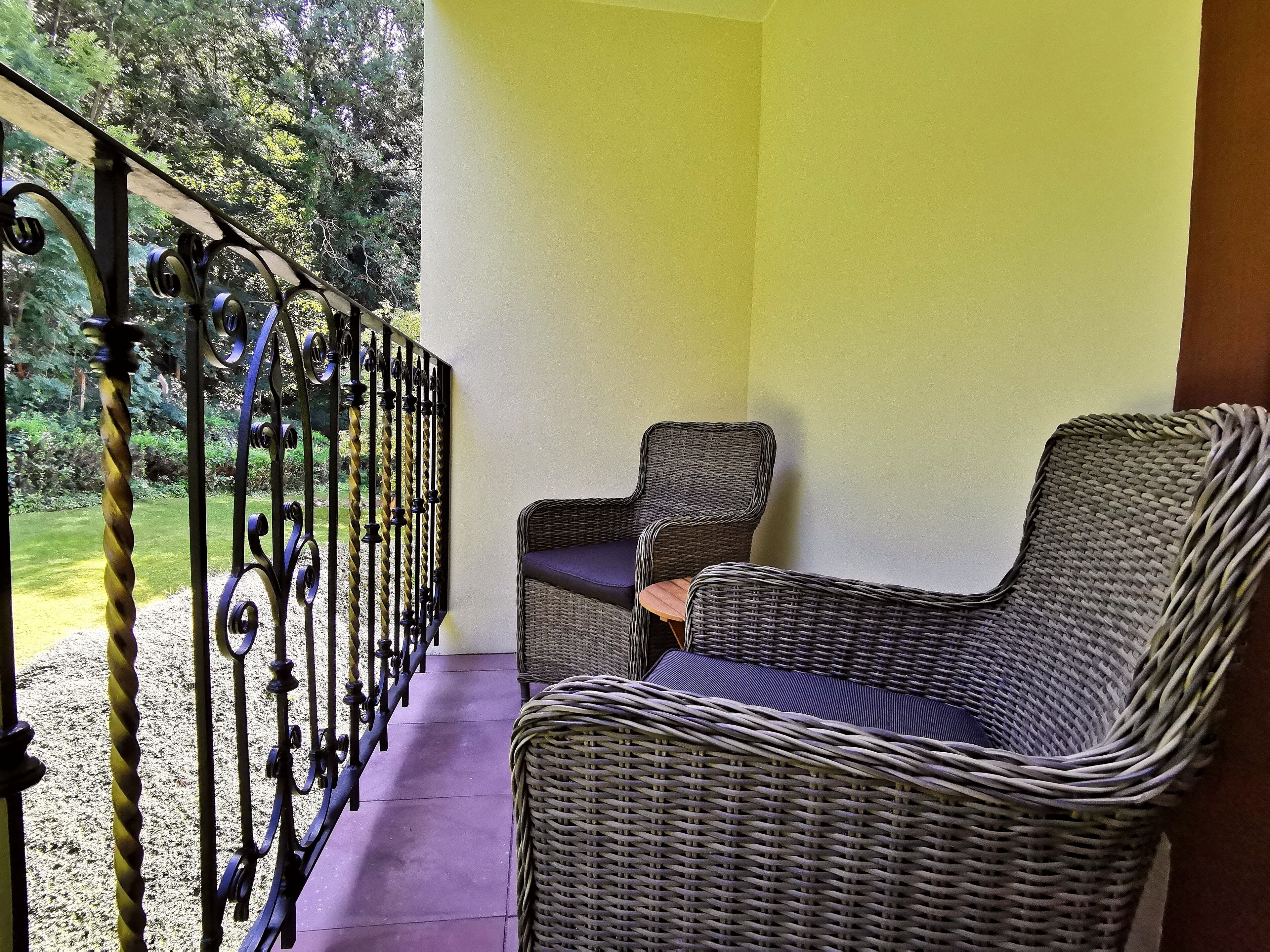 A balcony with wicker furniture and a metal railing.