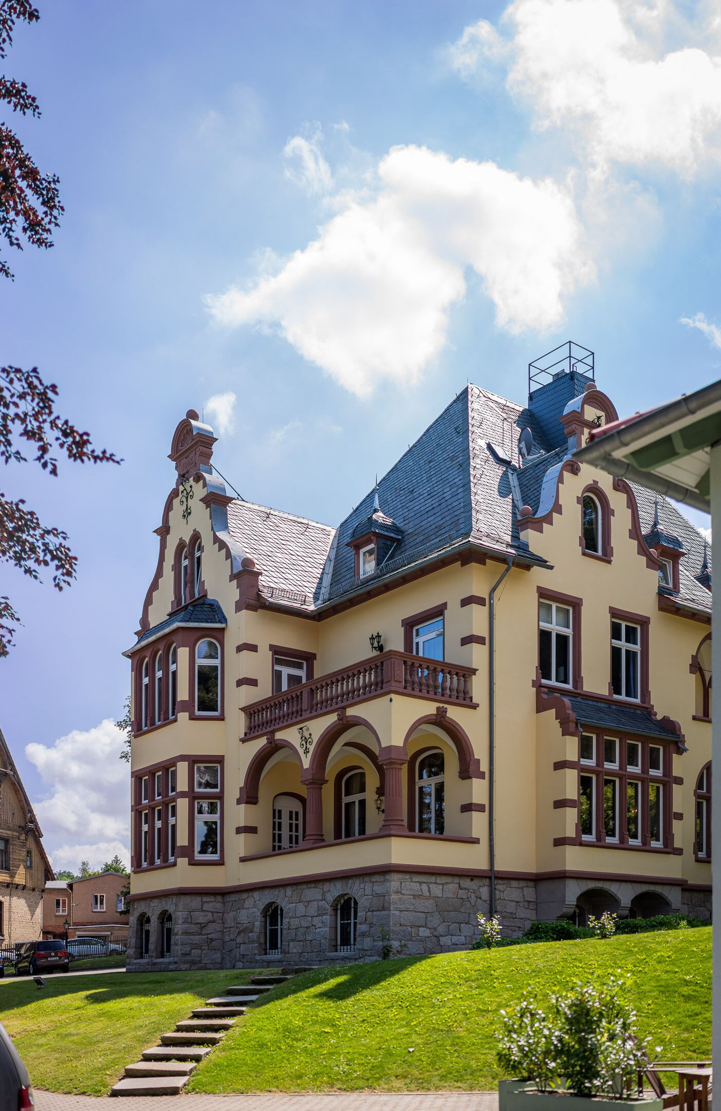Un edificio grande y ornamentado con un techo empinado, numerosas ventanas y un balcón destacado.