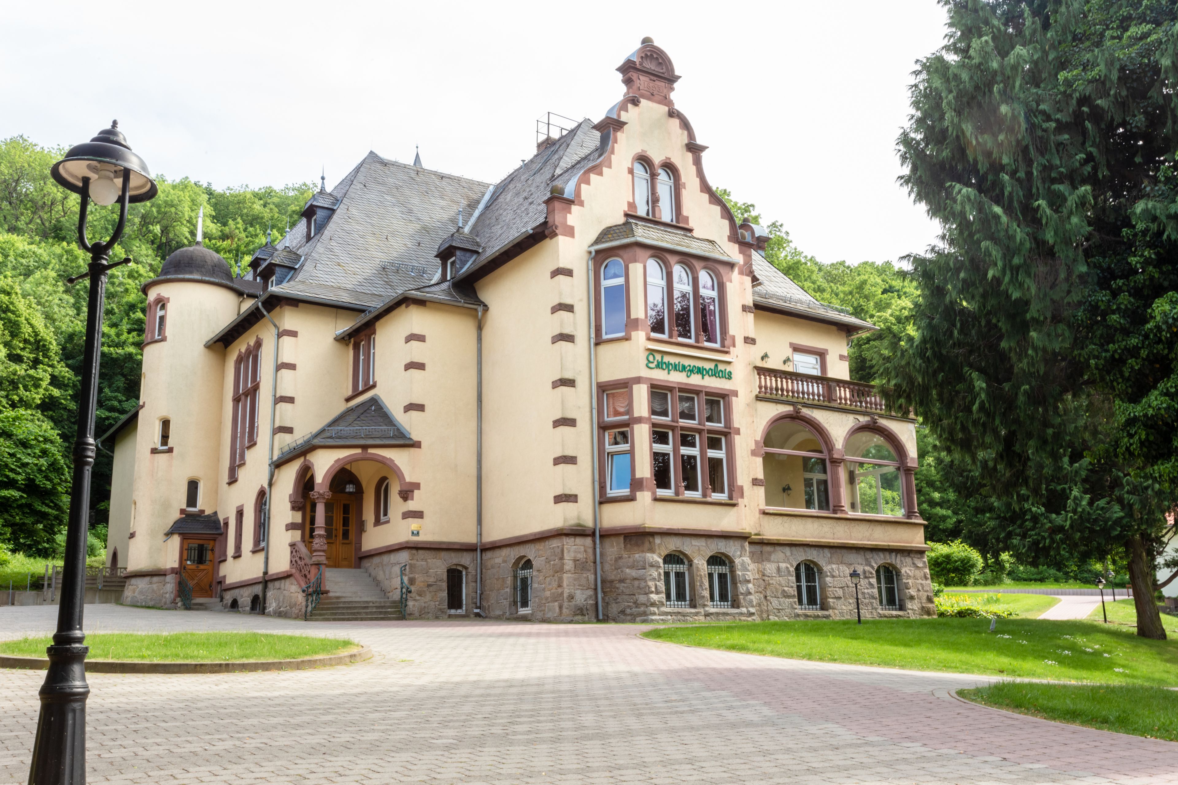A historic building with a prominent entrance, arched windows, and a balcony.