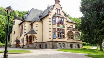 A historic building with a prominent entrance, arched windows, and a balcony.