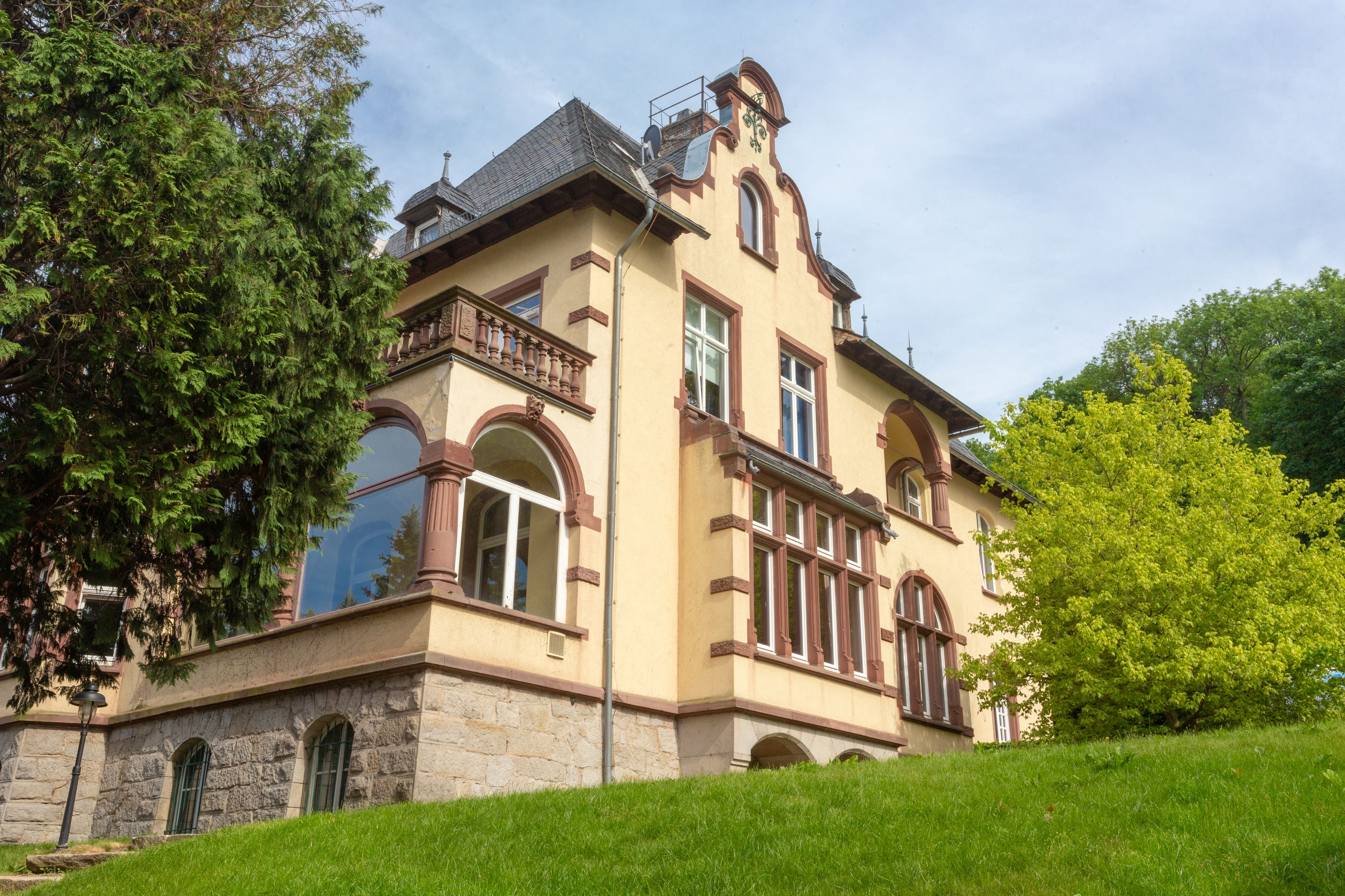 A historic building with a stone base, multiple windows, and a balcony.