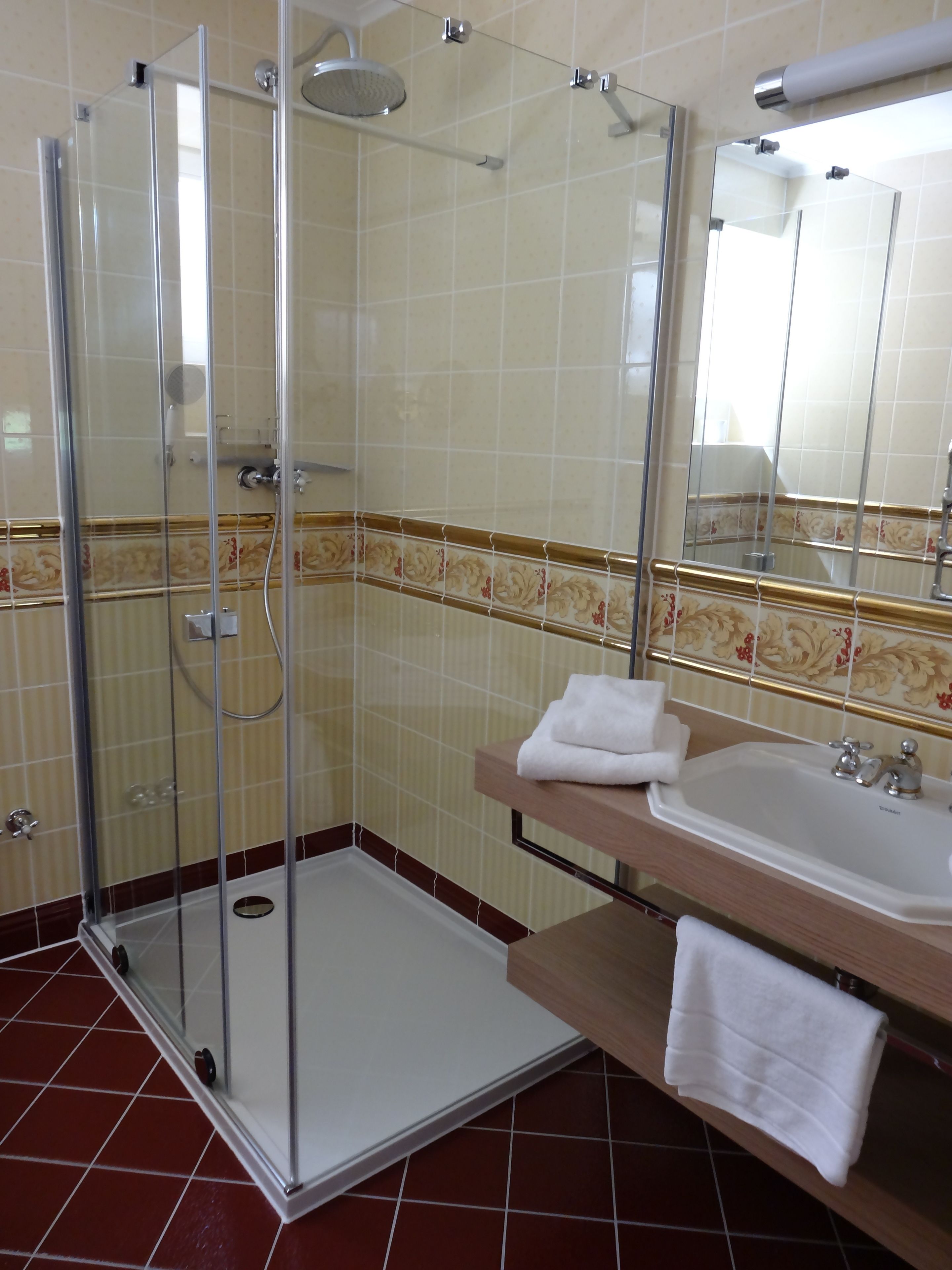 A bathroom with a glass-enclosed shower, a sink, and a mirror.