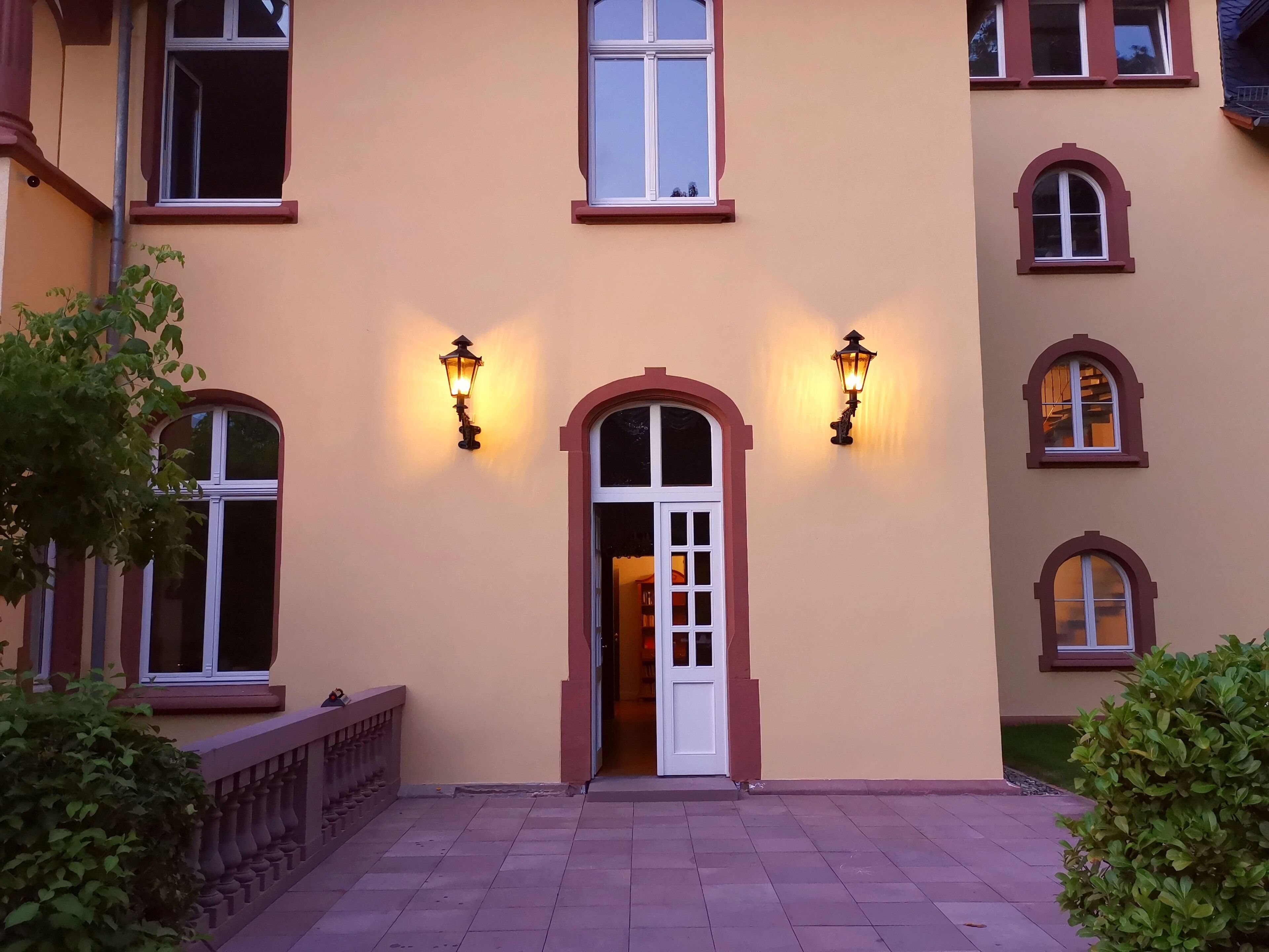 Un edificio con fachada color beige, varias ventanas y dos luces fijadas a la pared.