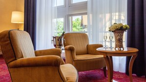 A room with two armchairs, a small table with a vase of flowers, and a lamp. - Hotel Erbprinzenpalais (Wernigerode)