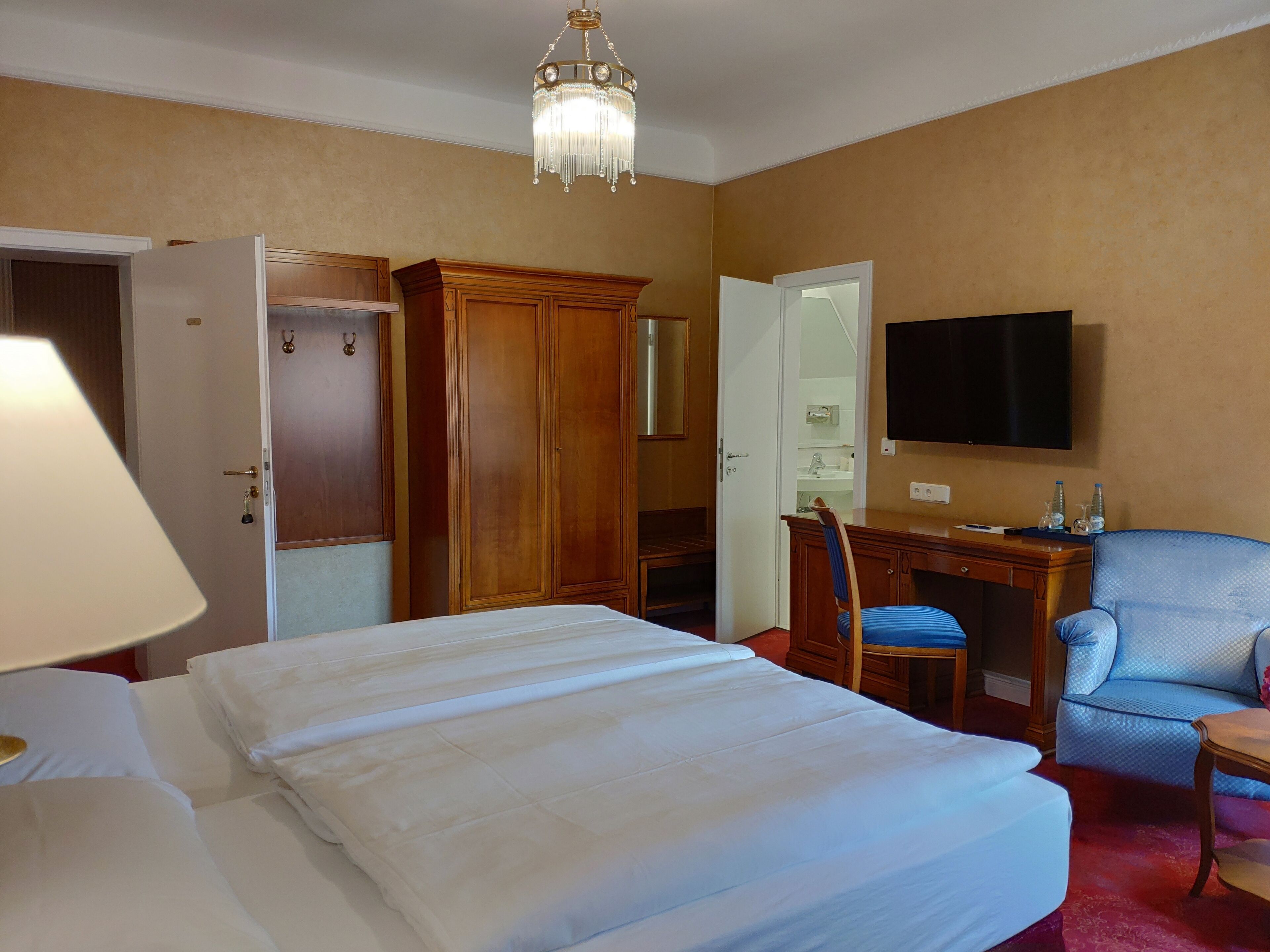 Una habitación de hotel con una cama, un escritorio, una silla, un televisor y un armario.