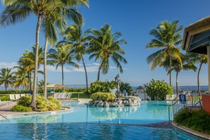 Ein Swimmingpool, umgeben von Palmen und einem Felsen.