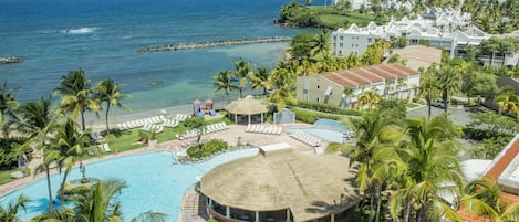 Un resort con piscina, sillas de descanso y vista al océano.