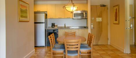 A compact kitchen with a dining area, equipped with a refrigerator, microwave, and a dishwasher.