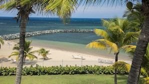 A beach with palm trees, a rocky breakwater, and a clear view of the ocean. - Aquarius Vacation Club at Dorado del Mar (Dorado)