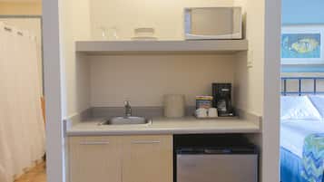 Una kitchenette compacta equipada con microondas, pileta y cafetera.