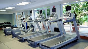 Un gimnasio con cintas de correr, elípticas y máquinas de pesas.