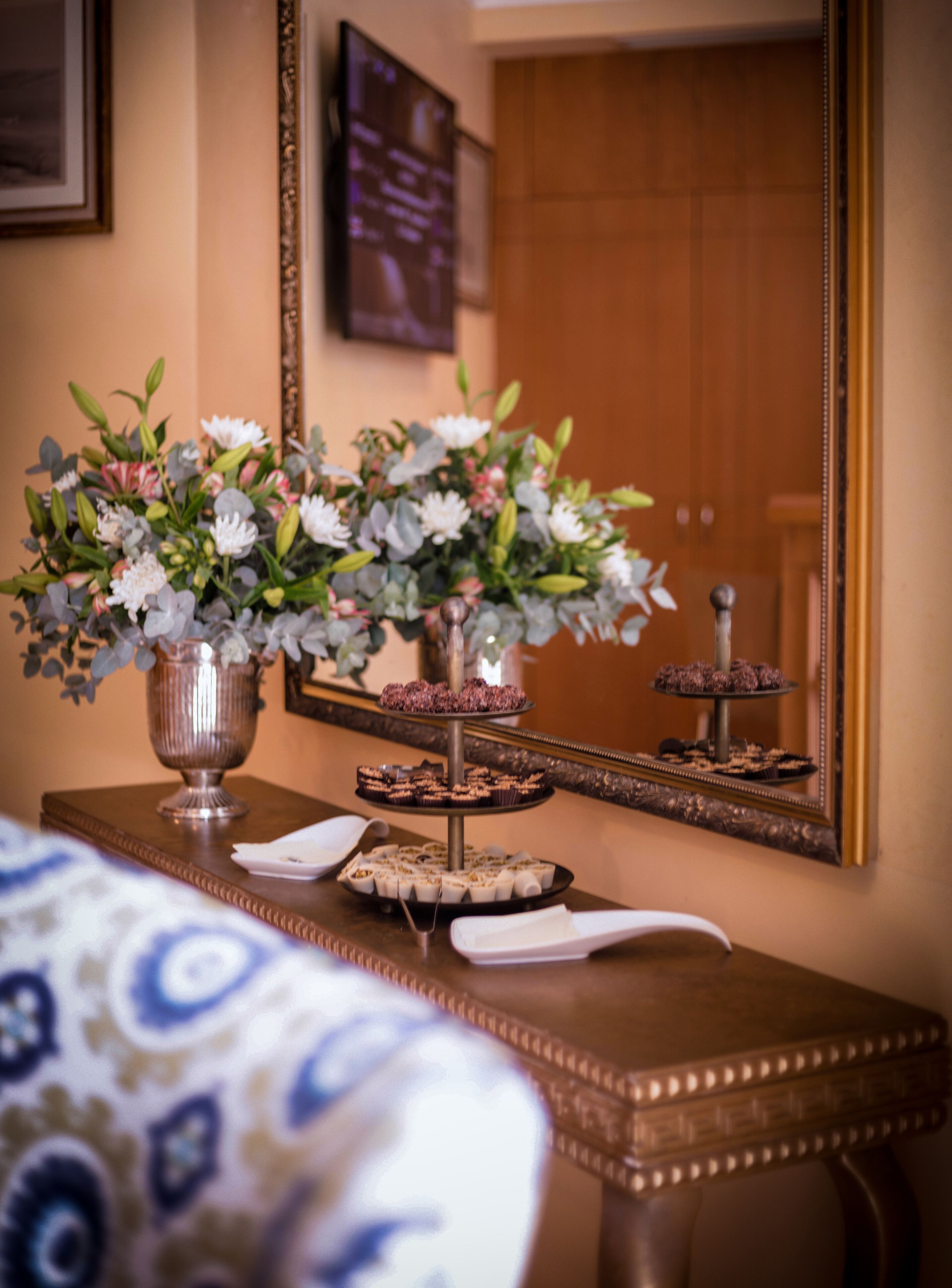 A table with a floral arrangement and a tiered dessert stand.