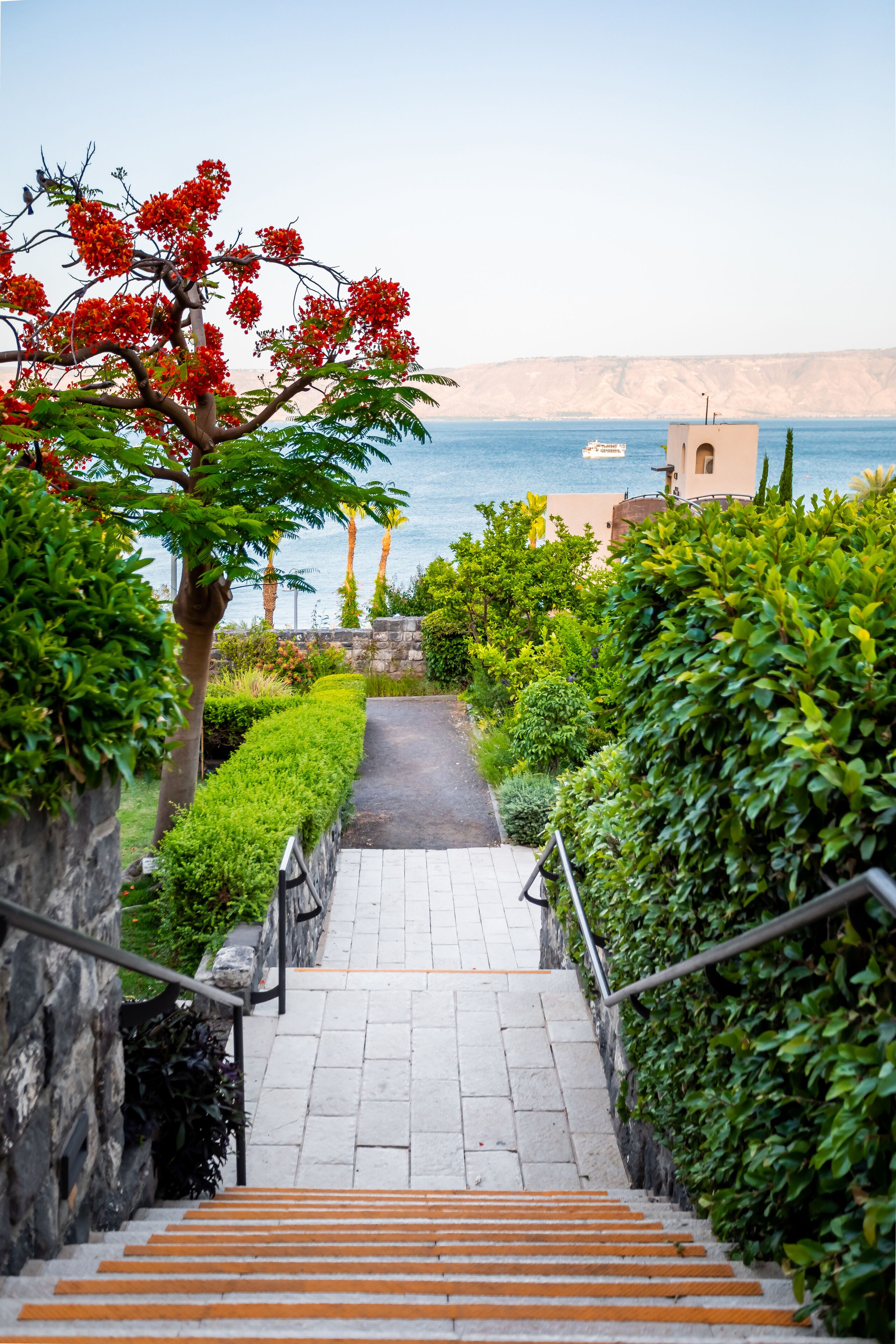 A staircase leading to a coastal area with a view of the sea and a building in the background.
