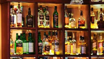 A bar area with shelves of various liquor bottles and a glass on the counter.