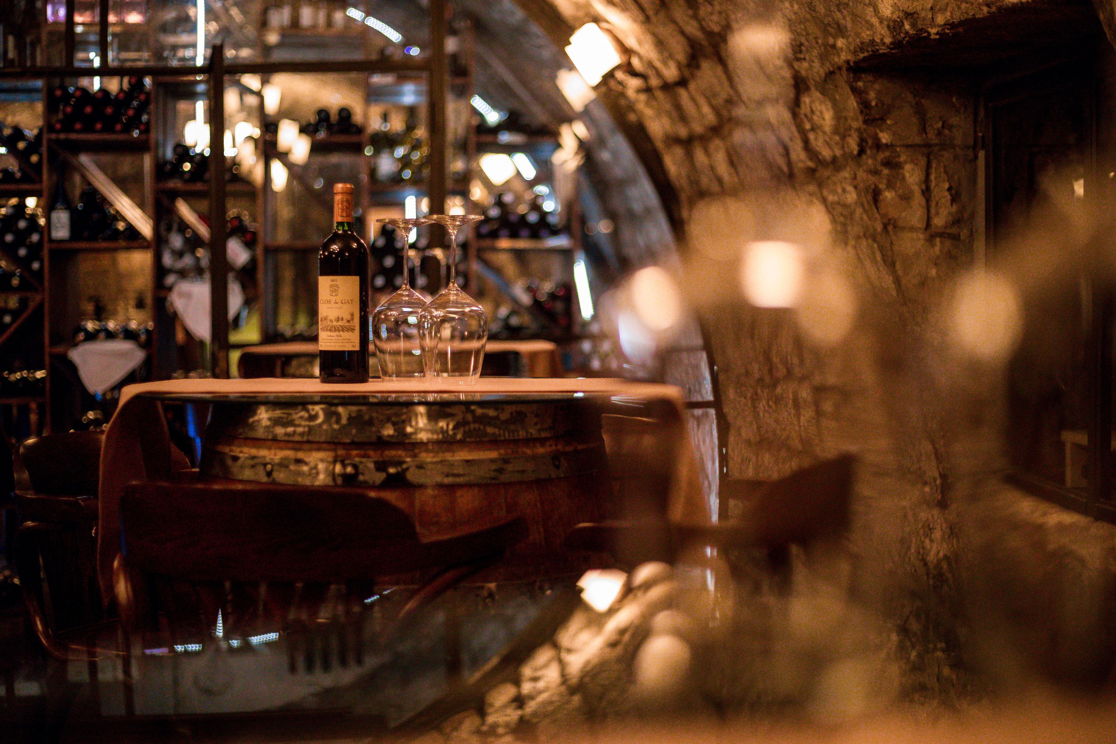 A bar area with a wooden counter, bottles, and glasses.