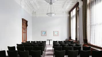 A conference room with rows of chairs, a table, and two framed artworks on the wall.