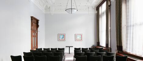 A conference room with rows of chairs, a table, and two framed artworks on the wall.