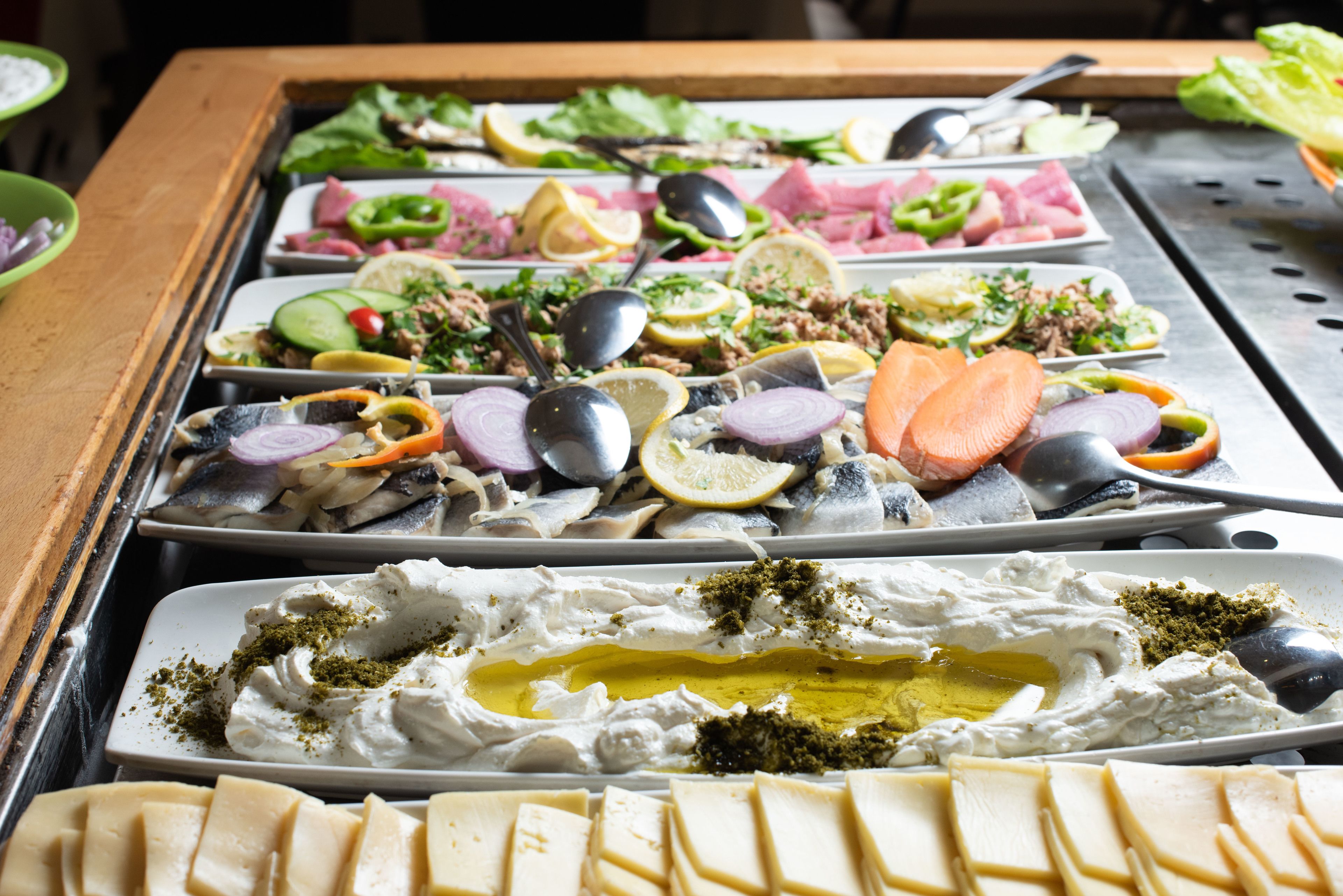 Un bufé con diversos platos, incluyendo mariscos, ensaladas y queso.