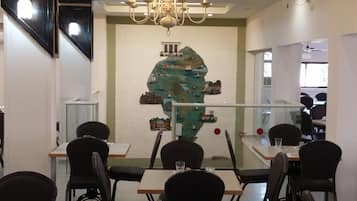 A dining area with tables and chairs, a chandelier, and a wall mural.