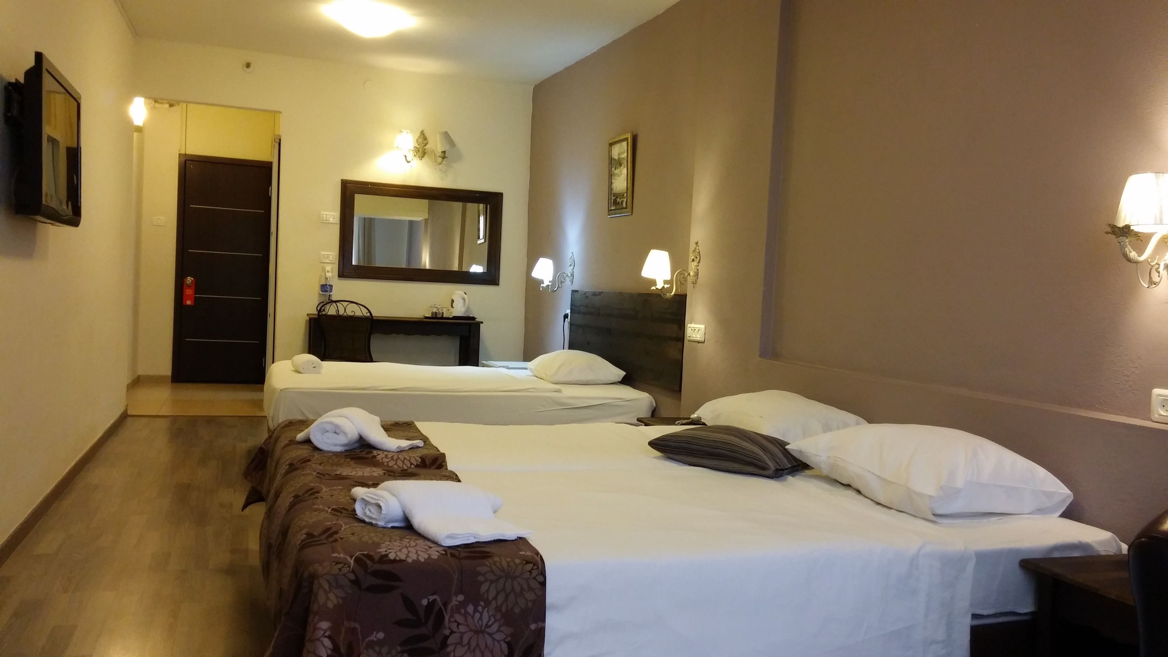 Una habitación de hotel con dos camas, un escritorio, un espejo y una puerta.