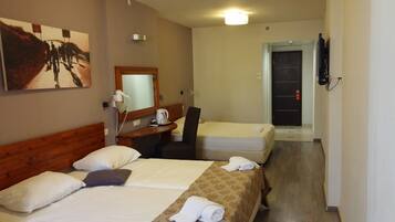 A hotel room with two beds, a desk, a chair, a mirror, and a television.