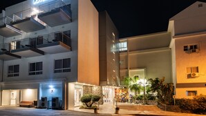 Un hôtel moderne, reconnaissable à son enseigne « ASTORIA GALILEE », doté de nombreux balcons, d’une entrée bien éclairée et d’un espace paysager agrémenté de plantes.