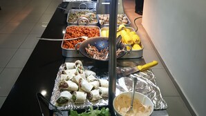 Un buffet proposant une variété de plats, notamment des tortillas, du maïs et des salades.