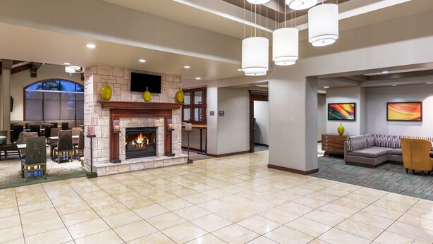 A spacious lobby with a fireplace, seating areas, and modern lighting fixtures.