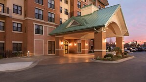 A multi-story hotel with a covered entrance, brick facade, and a parking lot.