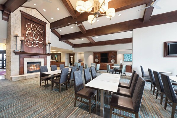 A spacious dining area with high ceilings, a fireplace, and modern lighting fixtures.