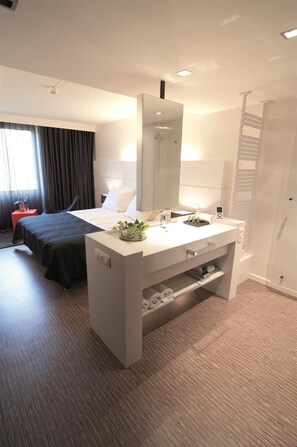 A modern hotel room with a large bed, a white vanity with a mirror, and a walk-in closet. - Best Western Hotel Arlux (Arlon)