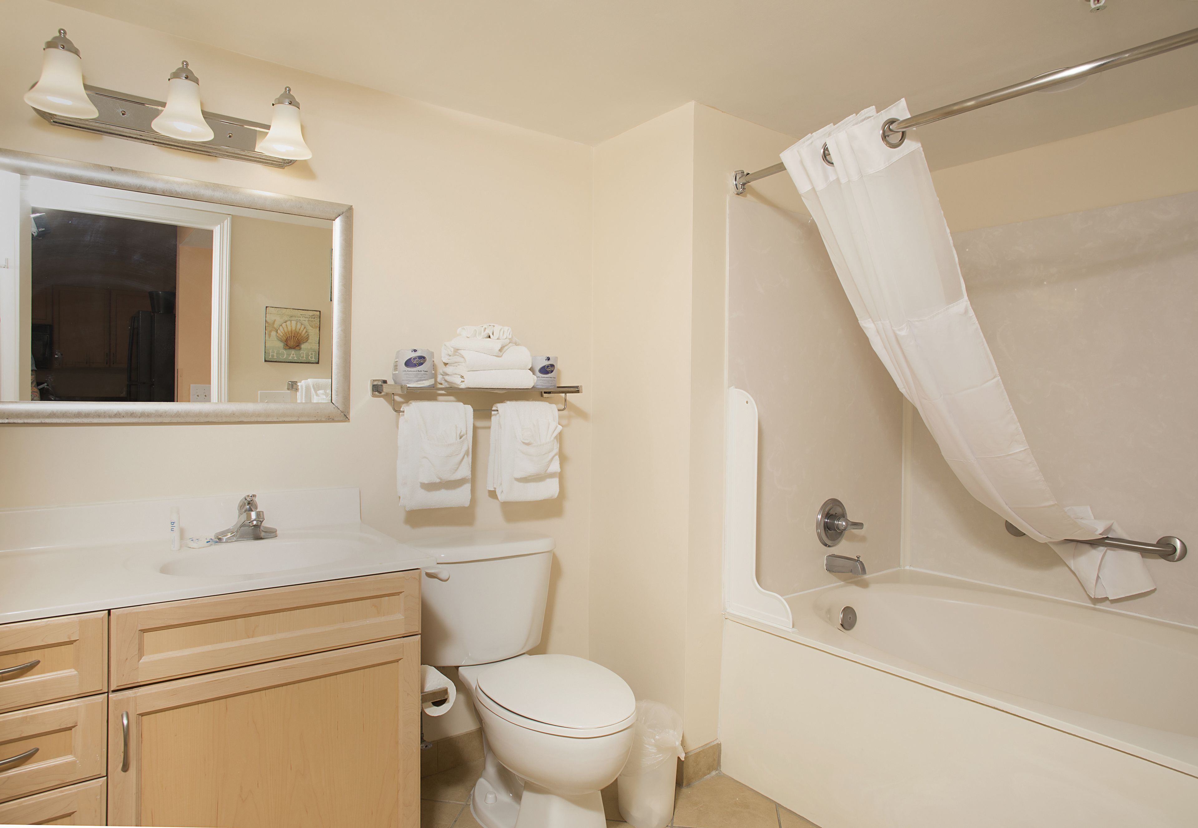 A bathroom with a sink, mirror, toilet, and bathtub.
