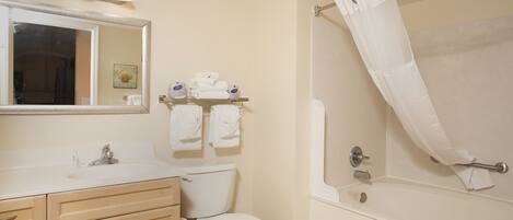 A bathroom with a sink, mirror, toilet, and bathtub.